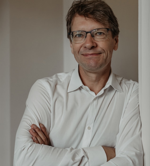 Porträt von Holger Langer in weißem Hemd, lächelnd mit verschränkten Armen
